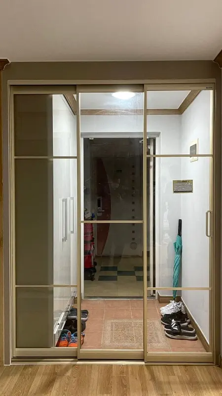 가로 바가 들어간 골드 톤 슬림 3연동 중문이 닫혀 있는 현관 정면