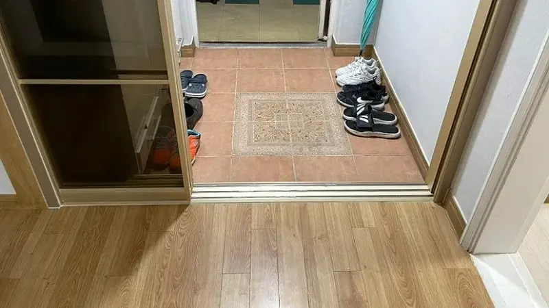 현관 타일과 우드 바닥 사이에 놓인 하부 레일과 몰딩 마감