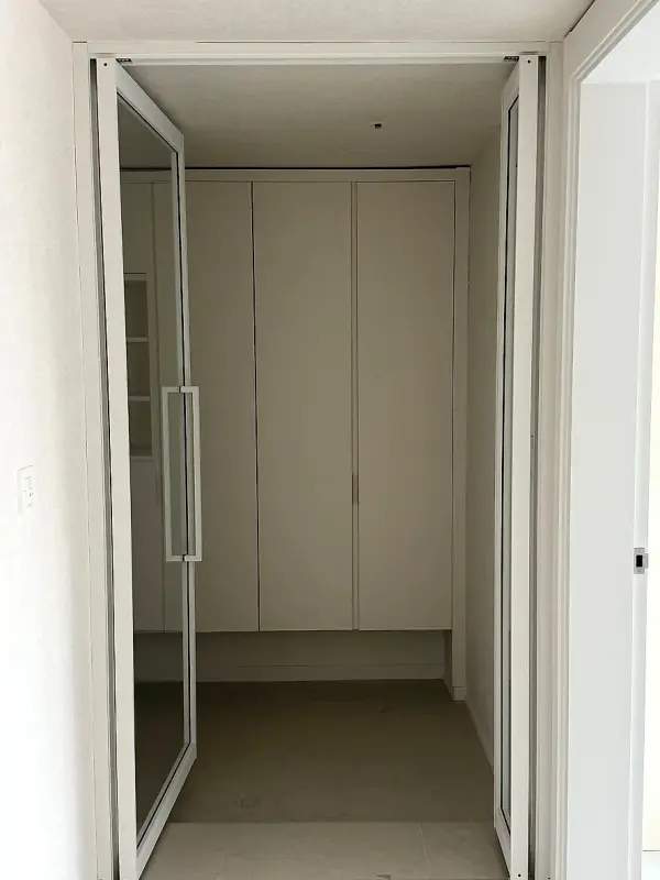 흰 붙박이장 앞에 설치를 마친 슬림한 화이트 프레임 스윙도어