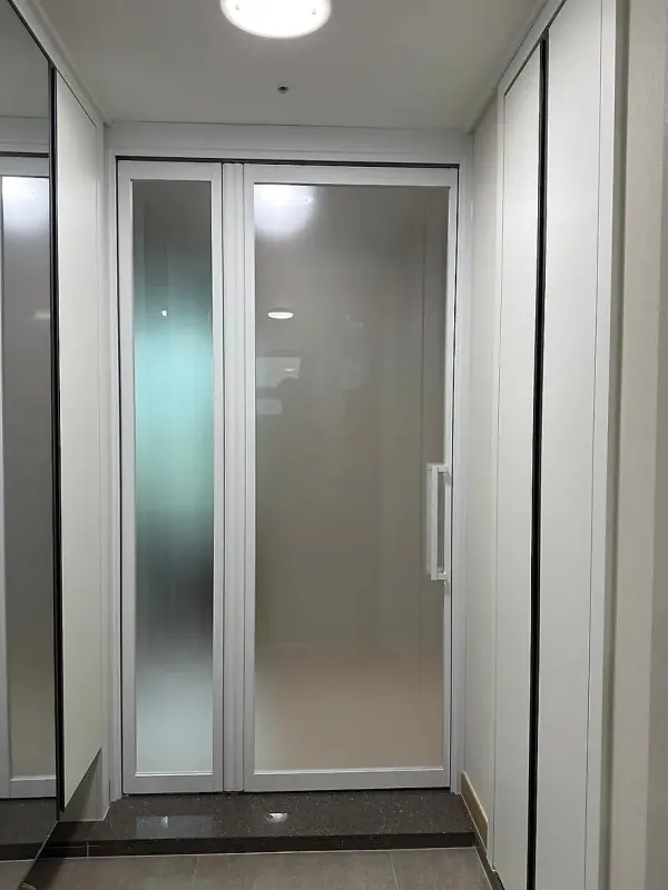 현관에서 본 닫힌 화이트 슬림 스윙폴딩도어와 백사틴유리