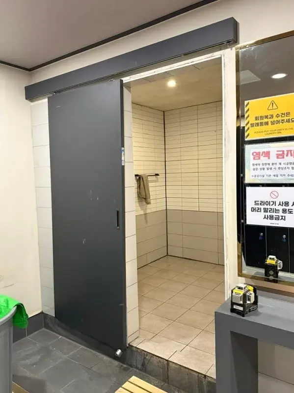샤워장 입구에 달려 있던 짙은 회색 미닫이문과 안쪽 타일 벽