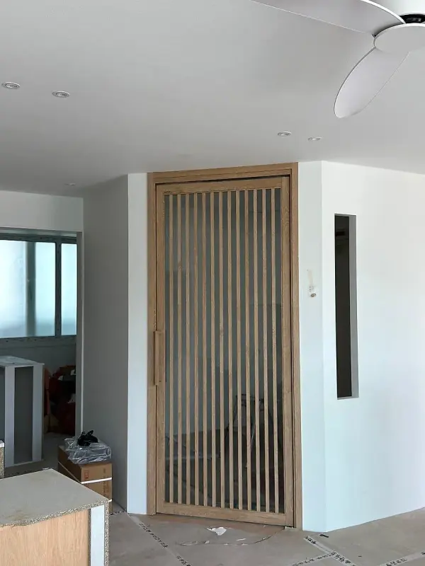 거실 쪽에서 멀리 바라본 나무 톤 간살 중문과 세로형 작은 창