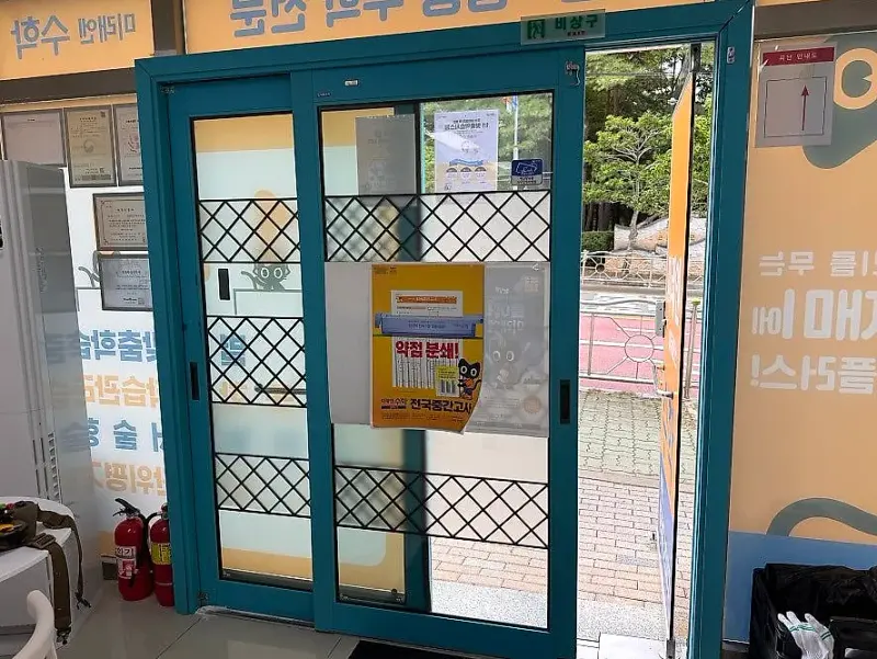 청록색 목재 프레임에 격자 무늬가 붙은 기존 2연동 출입문