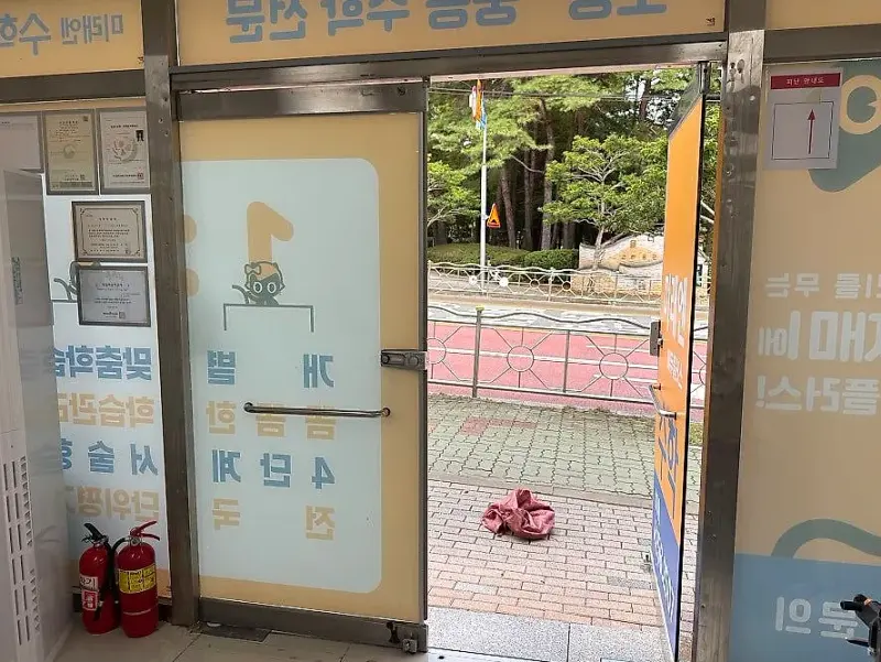 기존 문을 철거하고 문짝 하나만 기대어 둔 학원 입구