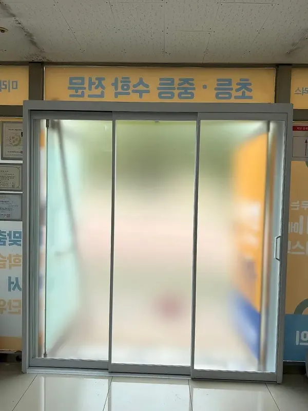 반투명 사틴유리 세 짝이 닫혀 있는 알루미늄 3연동 출입문