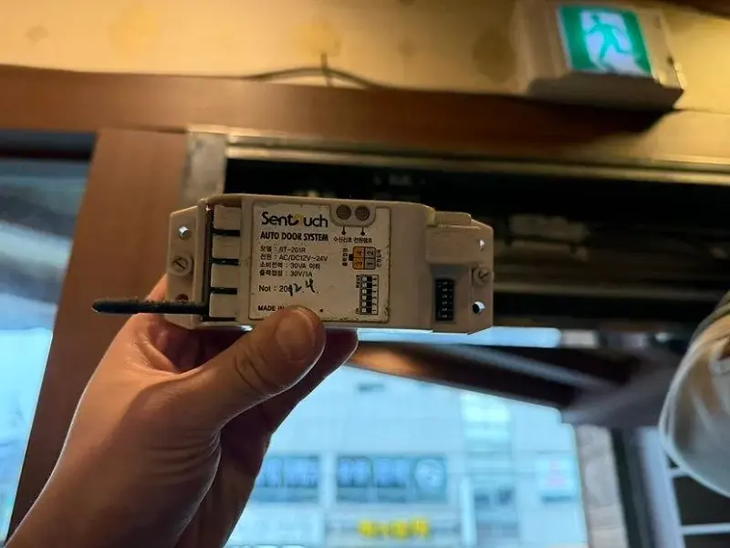 교체용 새 자동문 무선 터치 수신기를 손에 든 모습