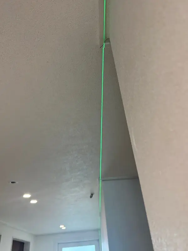 벽 모서리를 따라 세로로 비친 녹색 레이저 수직선