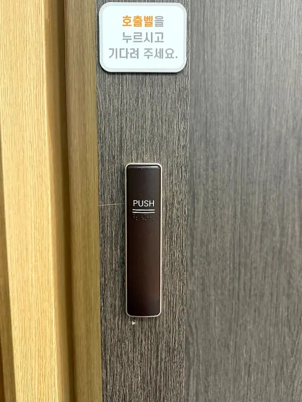 목재 루버 벽에 새로 부착된 검은색 PUSH 자동문 스위치