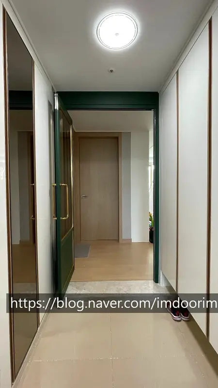 현관 쪽에서 거실 방향으로 본 닫힌 딥그린 중문과 복도