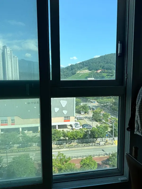 거실 쪽에서 바라본 아파트 창문과 바깥 산과 도로 풍경