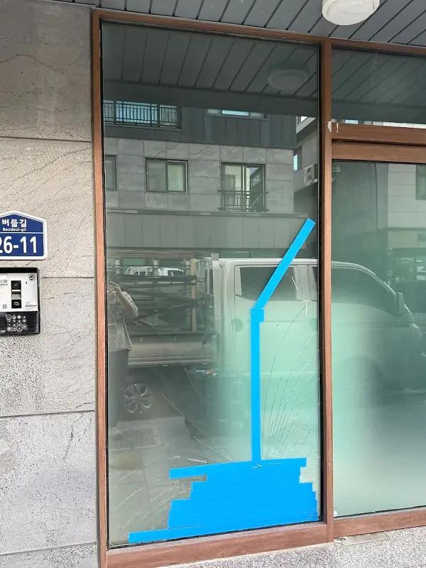 깨진 유리가 떨어지지 않도록 파란 테이프를 붙여 둔 모습