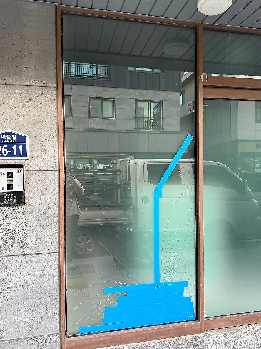 깨진 유리가 떨어지지 않도록 테이프를 붙여 둔 상가 전면 유리