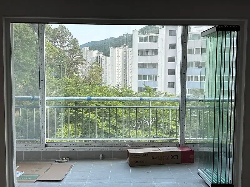 발코니 오른쪽 끝에 세워 둔 프레임 없는 유리 패널