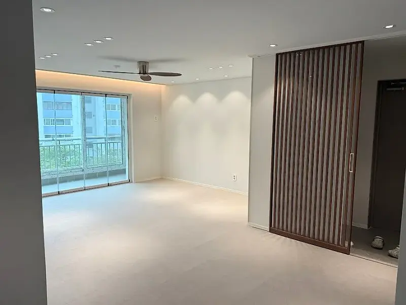 거실 한쪽에서 비스듬히 본 발코니 폴딩도어와 나무 간살 벽